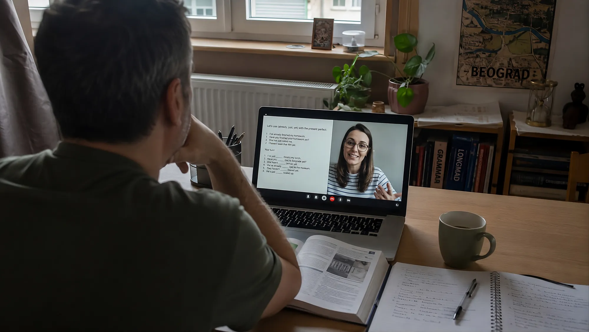 Polaznik na online času engleskog: predavačica na ekranu laptopa, otvorena knjiga i sveska na stolu